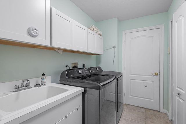 laundry area featuring cabinets, light tile patterned floors, washer and clothes dryer, and sink