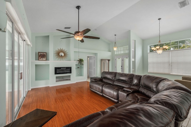 living room featuring hardwood / wood-style floors, ceiling fan with notable chandelier, vaulted ceiling, and a wealth of natural light