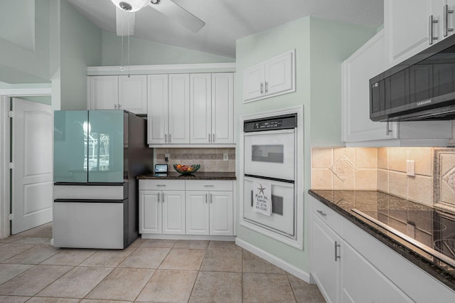 kitchen featuring stainless steel fridge, black electric stovetop, white double oven, light tile patterned floors, and white cabinets