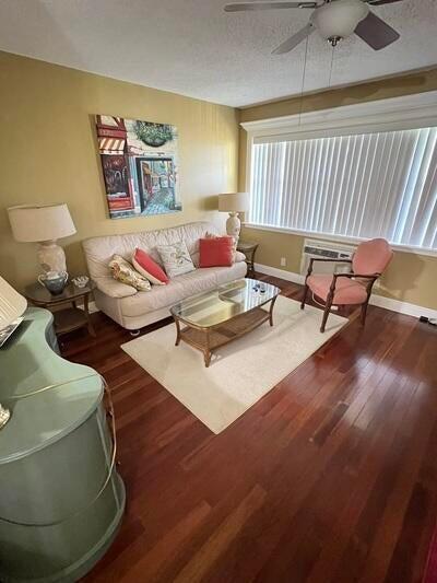 living room featuring a textured ceiling, ceiling fan, and dark hardwood / wood-style floors