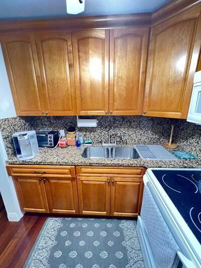 kitchen featuring sink, light stone counters, dark hardwood / wood-style floors, white appliances, and decorative backsplash