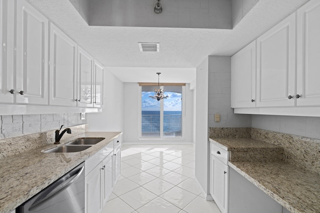 kitchen featuring sink, stainless steel dishwasher, light tile patterned floors, decorative light fixtures, and white cabinetry