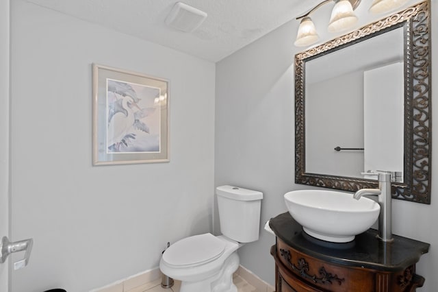 bathroom featuring tile patterned flooring, vanity, toilet, and a textured ceiling