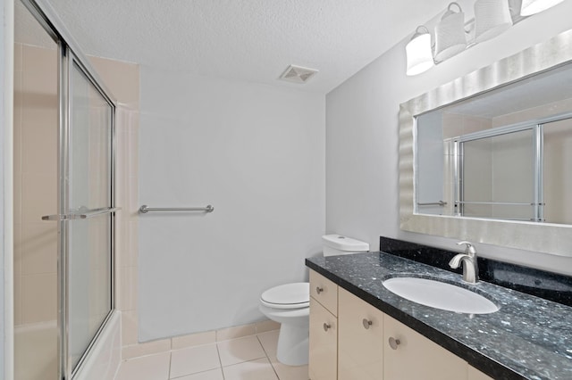 full bathroom with tile patterned floors, vanity, a textured ceiling, enclosed tub / shower combo, and toilet