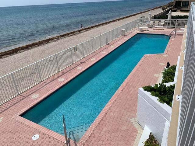 view of swimming pool with a patio area, a water view, and a view of the beach