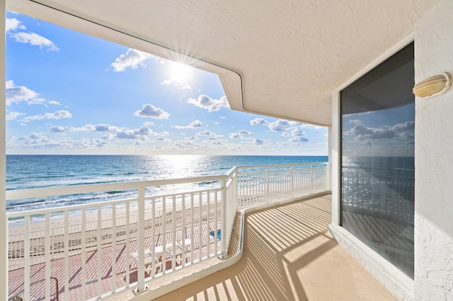 balcony with a water view and a view of the beach