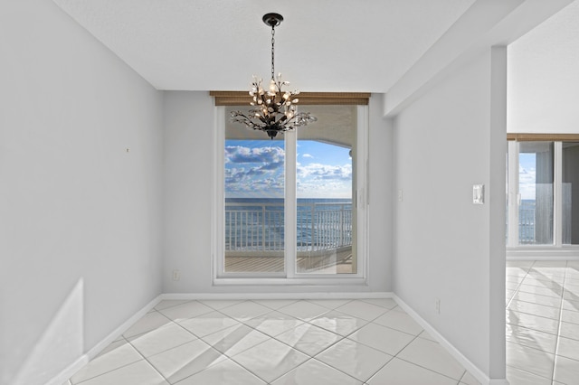 unfurnished dining area featuring a wealth of natural light, light tile patterned floors, and a notable chandelier