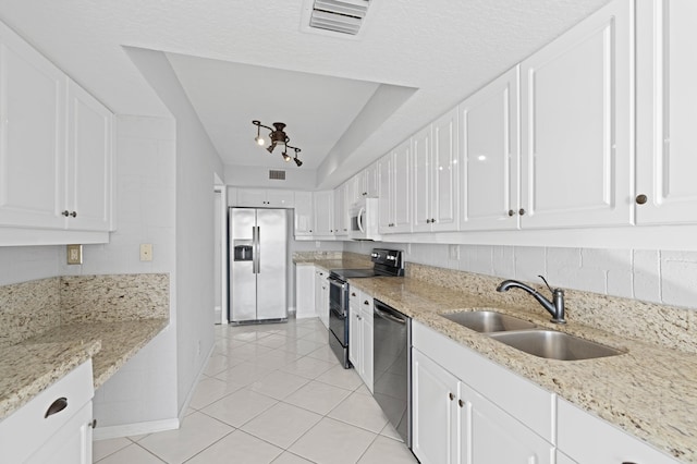 kitchen featuring light stone countertops, appliances with stainless steel finishes, sink, light tile patterned floors, and white cabinetry