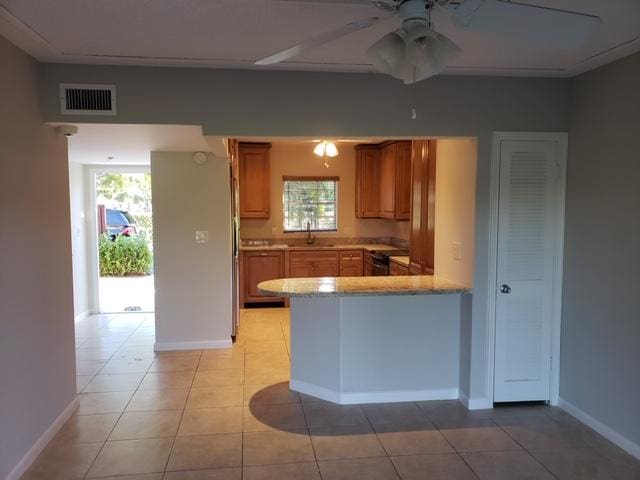 kitchen with black range with electric stovetop, ceiling fan, sink, kitchen peninsula, and light tile patterned flooring