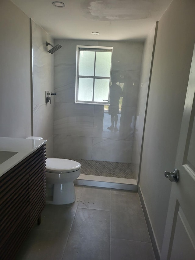 bathroom with toilet, vanity, and tiled shower