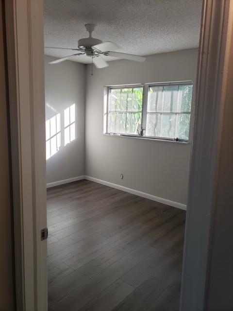 spare room with ceiling fan, dark wood-type flooring, and a textured ceiling