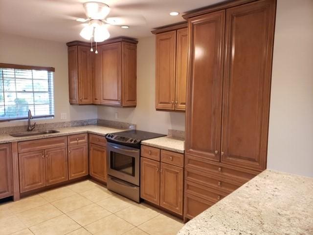 kitchen with light stone countertops, sink, ceiling fan, electric stove, and light tile patterned floors