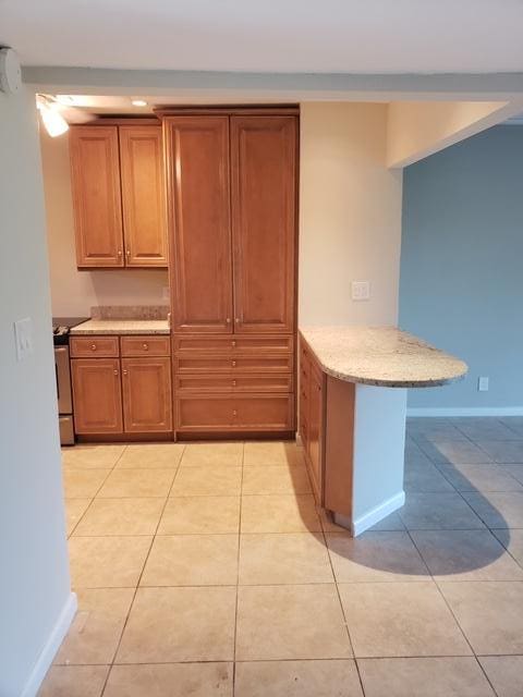 kitchen with kitchen peninsula, a kitchen bar, and light tile patterned flooring