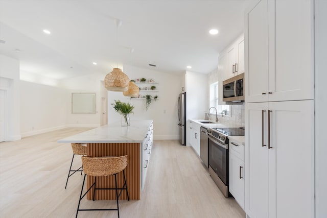 kitchen featuring light stone countertops, a center island, stainless steel appliances, lofted ceiling, and white cabinets