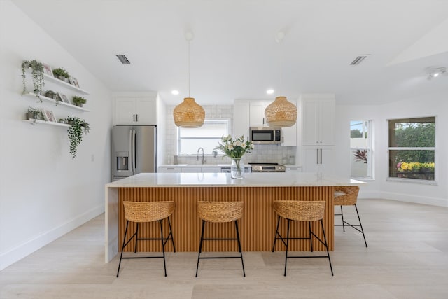 kitchen with backsplash, a large island, white cabinets, and stainless steel appliances