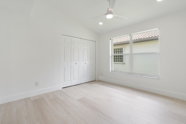 unfurnished bedroom featuring ceiling fan, a closet, lofted ceiling, and light hardwood / wood-style flooring