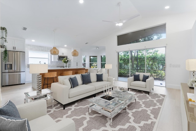 living room featuring ceiling fan, light wood-type flooring, and lofted ceiling