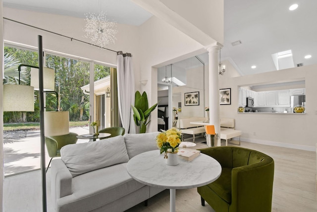 living room featuring vaulted ceiling, light hardwood / wood-style floors, and an inviting chandelier