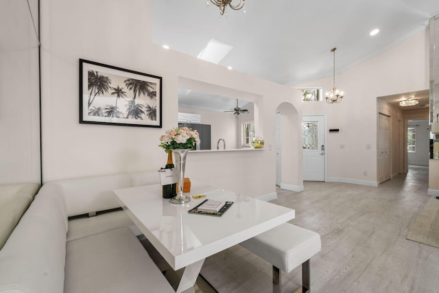 dining area with high vaulted ceiling, light hardwood / wood-style floors, and ceiling fan with notable chandelier