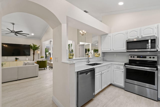 kitchen with white cabinets, sink, stainless steel appliances, and vaulted ceiling