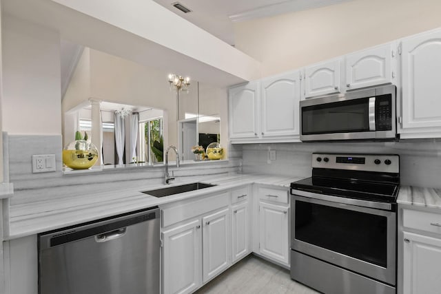 kitchen with appliances with stainless steel finishes, white cabinetry, a notable chandelier, and sink