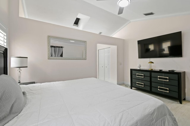 bedroom featuring light wood-type flooring, ornamental molding, vaulted ceiling, ceiling fan, and a closet