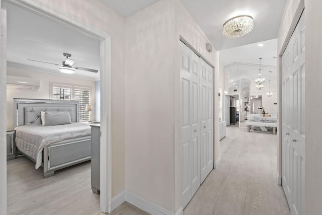 hall with a wall mounted air conditioner, light hardwood / wood-style floors, and a notable chandelier