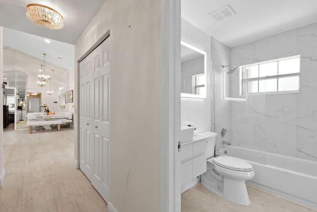 full bathroom with hardwood / wood-style floors, vaulted ceiling, toilet, vanity, and tiled shower / bath