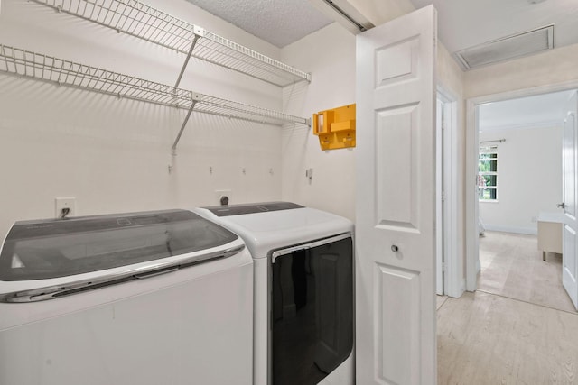 laundry area with washer and dryer and light wood-type flooring