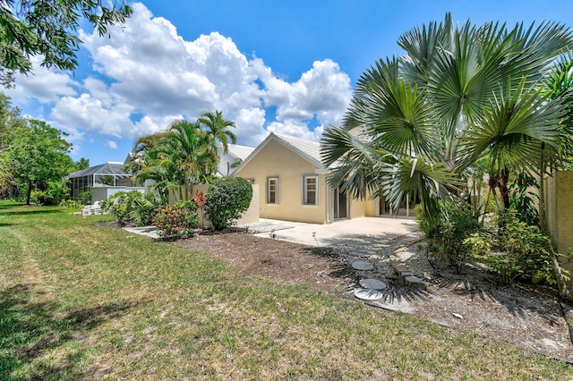 rear view of property with a lawn and a lanai