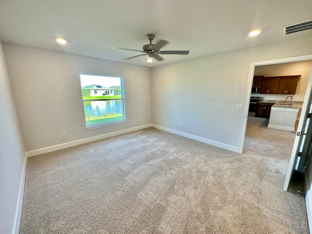 carpeted spare room featuring ceiling fan and sink