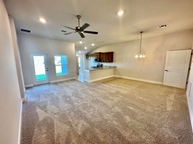 unfurnished living room with light carpet, ceiling fan with notable chandelier, and lofted ceiling