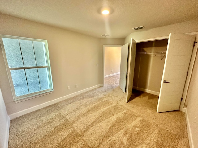 unfurnished bedroom with light colored carpet, a textured ceiling, and a closet