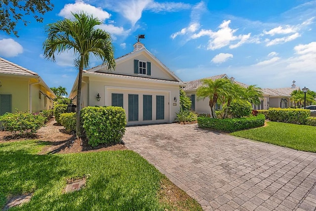 view of front of house with a chimney, a front yard, and stucco siding