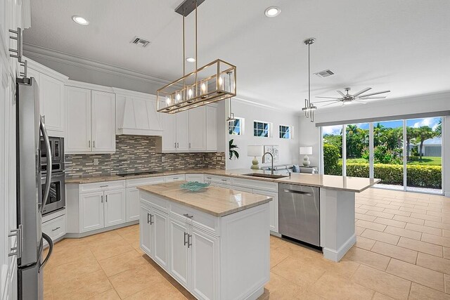 kitchen with stainless steel appliances, sink, decorative light fixtures, custom exhaust hood, and a center island