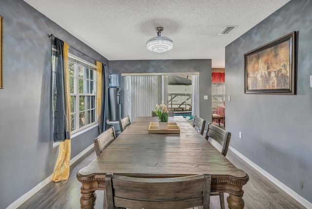 dining space with dark wood-type flooring and a textured ceiling