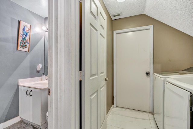 laundry area featuring independent washer and dryer, a textured ceiling, and sink