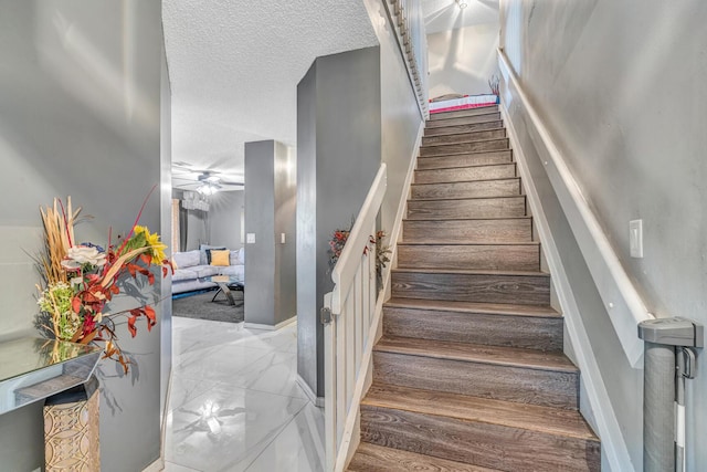 staircase featuring hardwood / wood-style floors, a textured ceiling, and ceiling fan