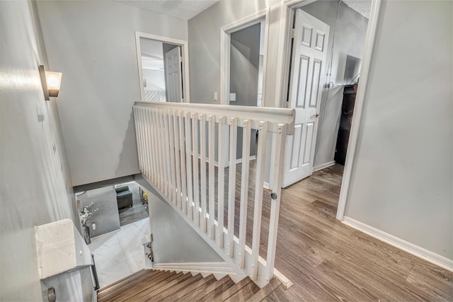 stairs featuring hardwood / wood-style floors and a textured ceiling