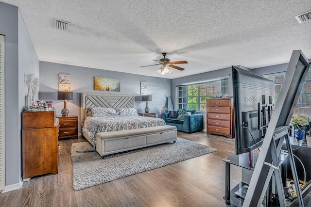 bedroom featuring hardwood / wood-style floors, ceiling fan, and a textured ceiling