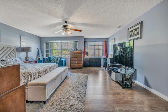 bedroom with ceiling fan, wood-type flooring, and a textured ceiling