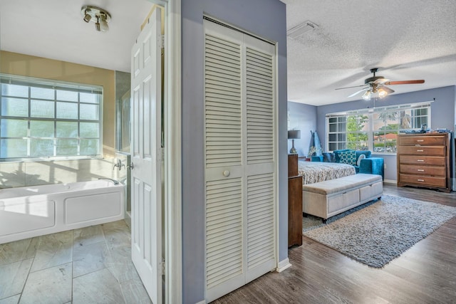 bedroom featuring ceiling fan, wood-type flooring, and a textured ceiling