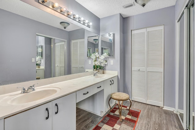 bathroom featuring hardwood / wood-style floors, vanity, and a textured ceiling