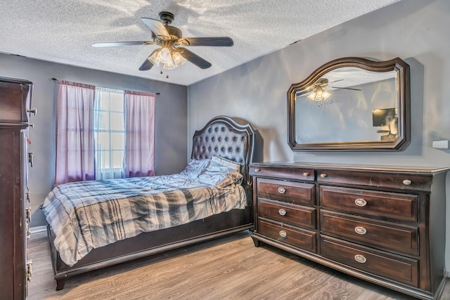 bedroom with a textured ceiling, light wood-type flooring, and ceiling fan