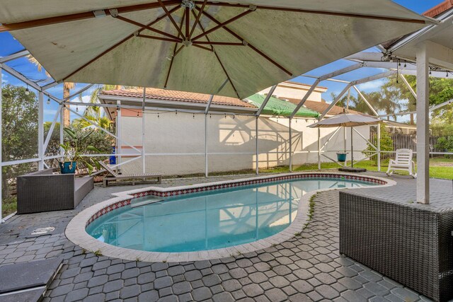 view of pool with glass enclosure and a patio