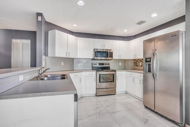 kitchen with white cabinets, sink, appliances with stainless steel finishes, and a textured ceiling