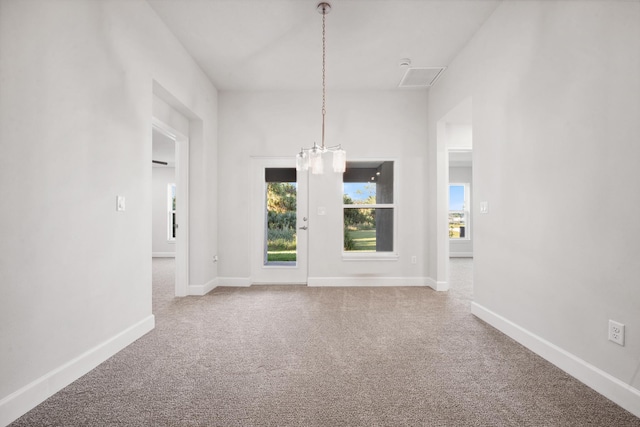 carpeted empty room with a notable chandelier