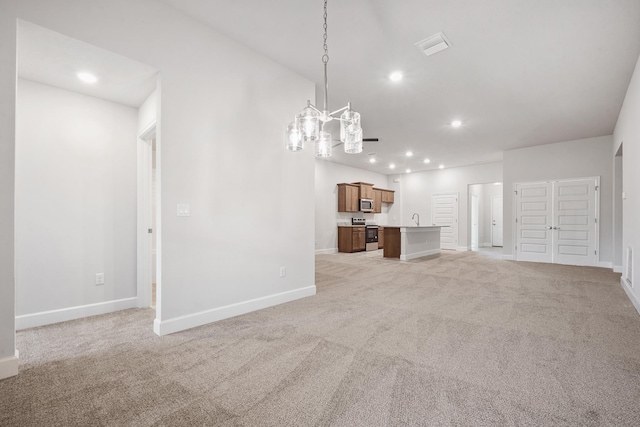 unfurnished living room featuring light carpet, a notable chandelier, and sink