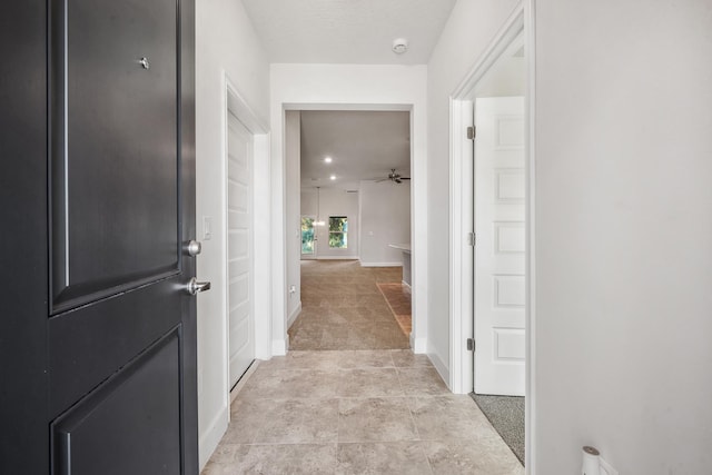 corridor featuring light colored carpet and a textured ceiling