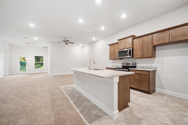 kitchen featuring a kitchen island with sink, light carpet, sink, ceiling fan, and stainless steel appliances